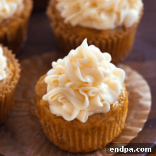 Delicious Sweet Potato Cupcakes generously topped with fluffy marshmallow frosting and a sprinkle of cinnamon.