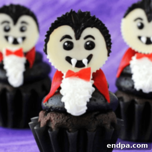 Spooky Dracula Cupcakes featuring a chocolate cupcake base, a white chocolate Reese's cup head, and edible fangs.