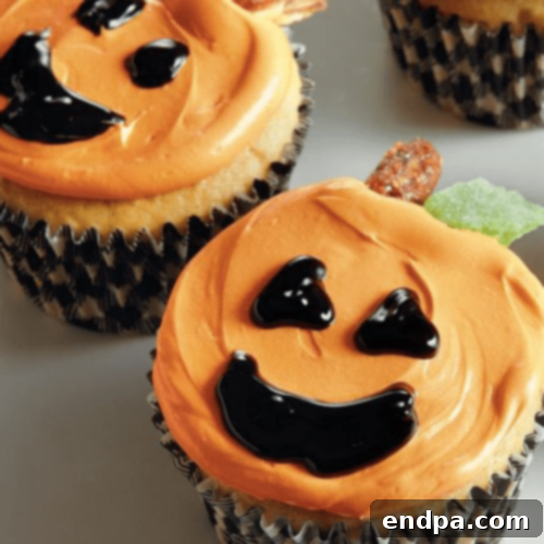 Cheerful Jack-O-Lantern Cupcakes decorated with orange frosting and classic carved pumpkin faces.