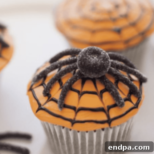 Classic Spiderweb Cupcakes with dark frosting and an intricate white icing spiderweb design.