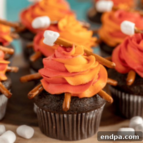 Whimsical Easy Campfire Cupcakes with chocolate cake, fluffy frosting, and a toasted marshmallow on a pretzel stick.