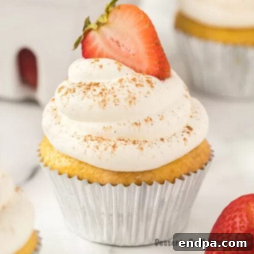 Moist Tres Leches Cupcakes topped with whipped cream, cinnamon, and a fresh strawberry slice.
