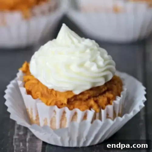 Fluffy pumpkin cupcakes generously topped with creamy cream cheese frosting and a sprinkle of cinnamon.
