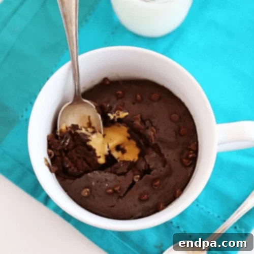 A peanut butter chocolate mug cake with a spoonful taken out.