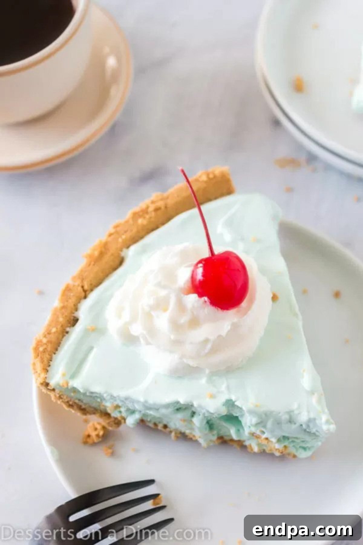 A vibrant slice of Kool-Aid pie, showcasing its smooth, colorful filling and delicate graham cracker crust, served on a white plate, perfect for a refreshing dessert.