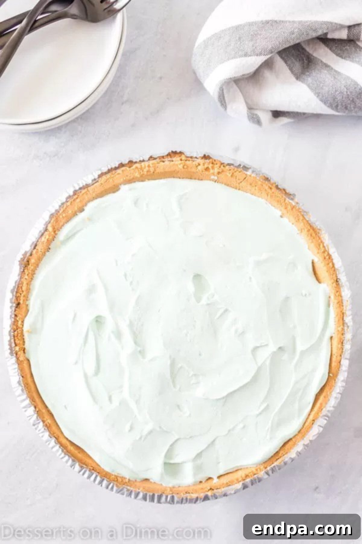 A vibrant blue Kool-Aid pie filling smoothly poured into a graham cracker crust, ready to be refrigerated and set.