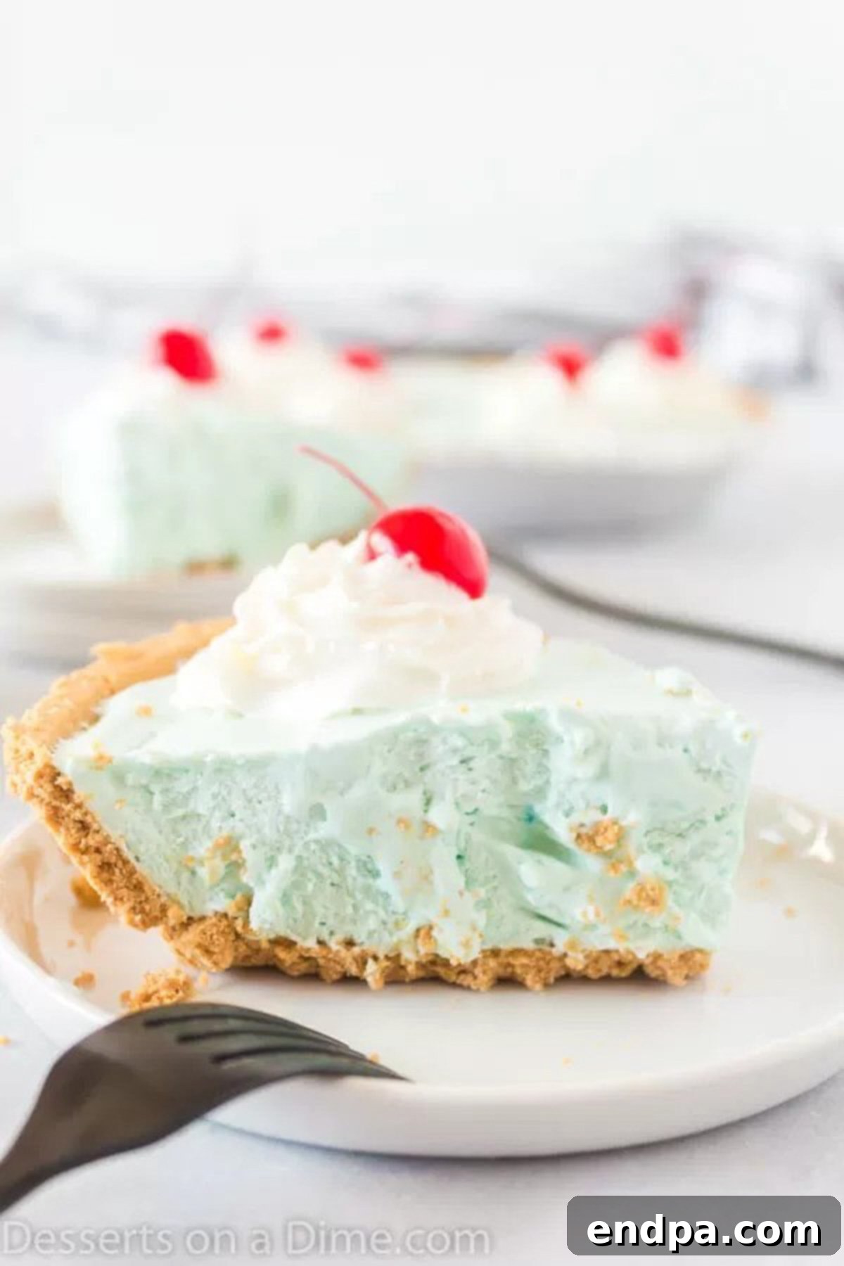 A close-up of a perfectly chilled slice of blue Kool-Aid pie, sitting on a white plate, highlighting its smooth texture and refreshing appearance.