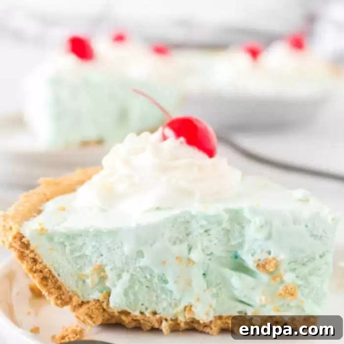 A tempting slice of blue Kool-Aid pie on a plate, indicating a refreshing and easy-to-make dessert.