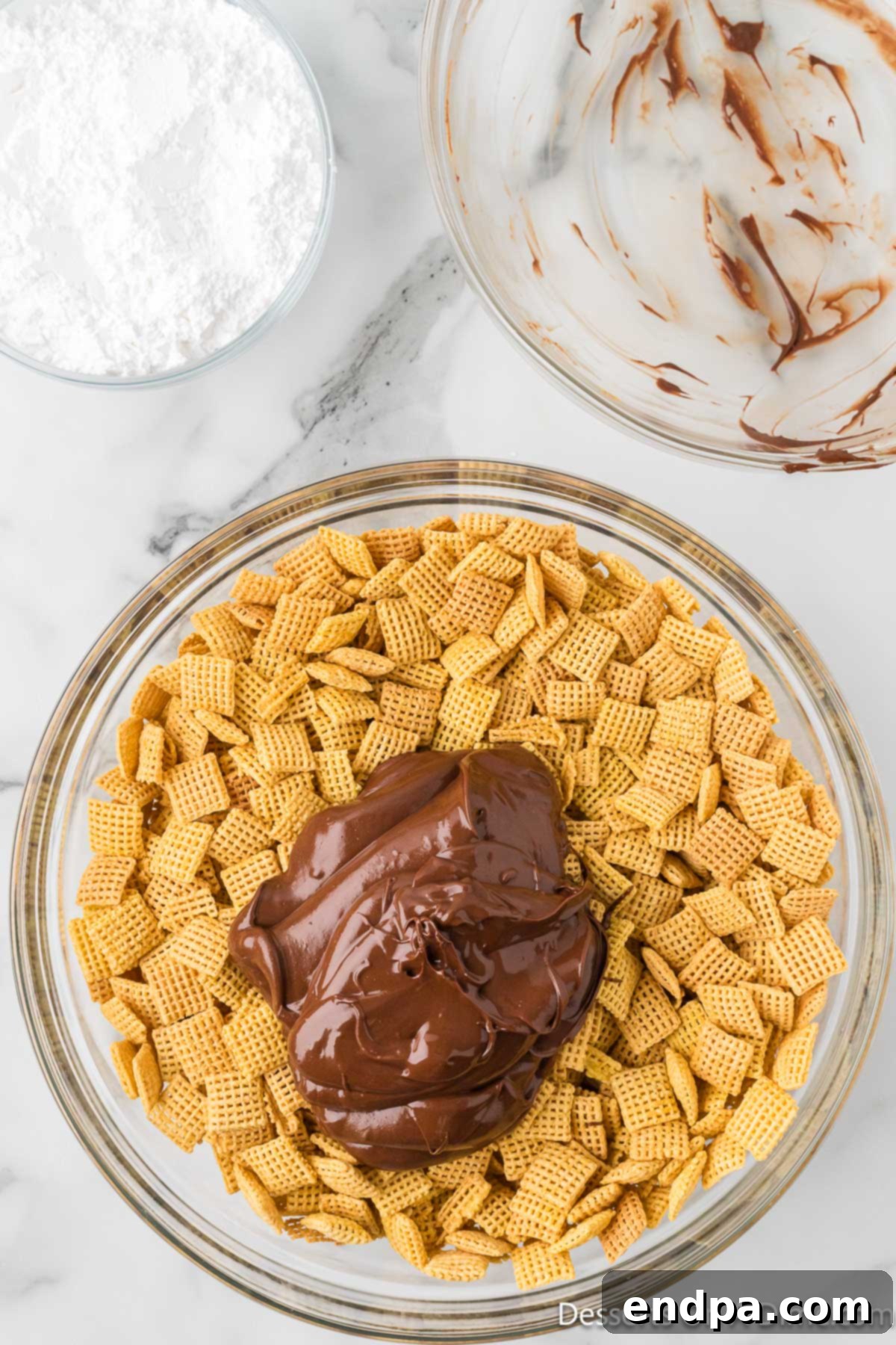 Smores Indulgence Mix 6 Crispy Chex cereal being coated with the melted chocolate and peanut butter mixture in a large bowl.