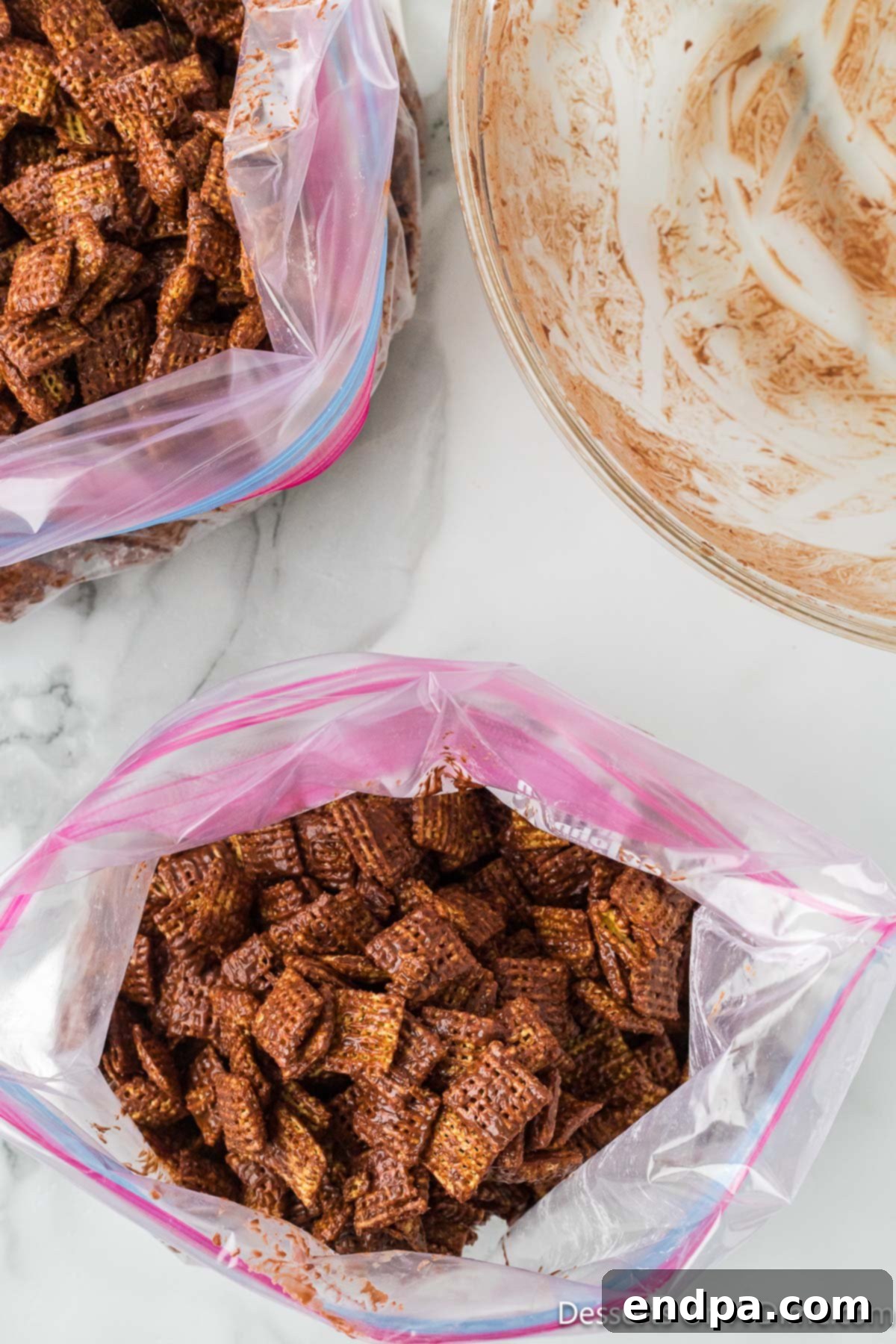 Smores Indulgence Mix 8 Chocolate-coated cereal thoroughly mixed with powdered sugar inside a sealed ziplock bag.