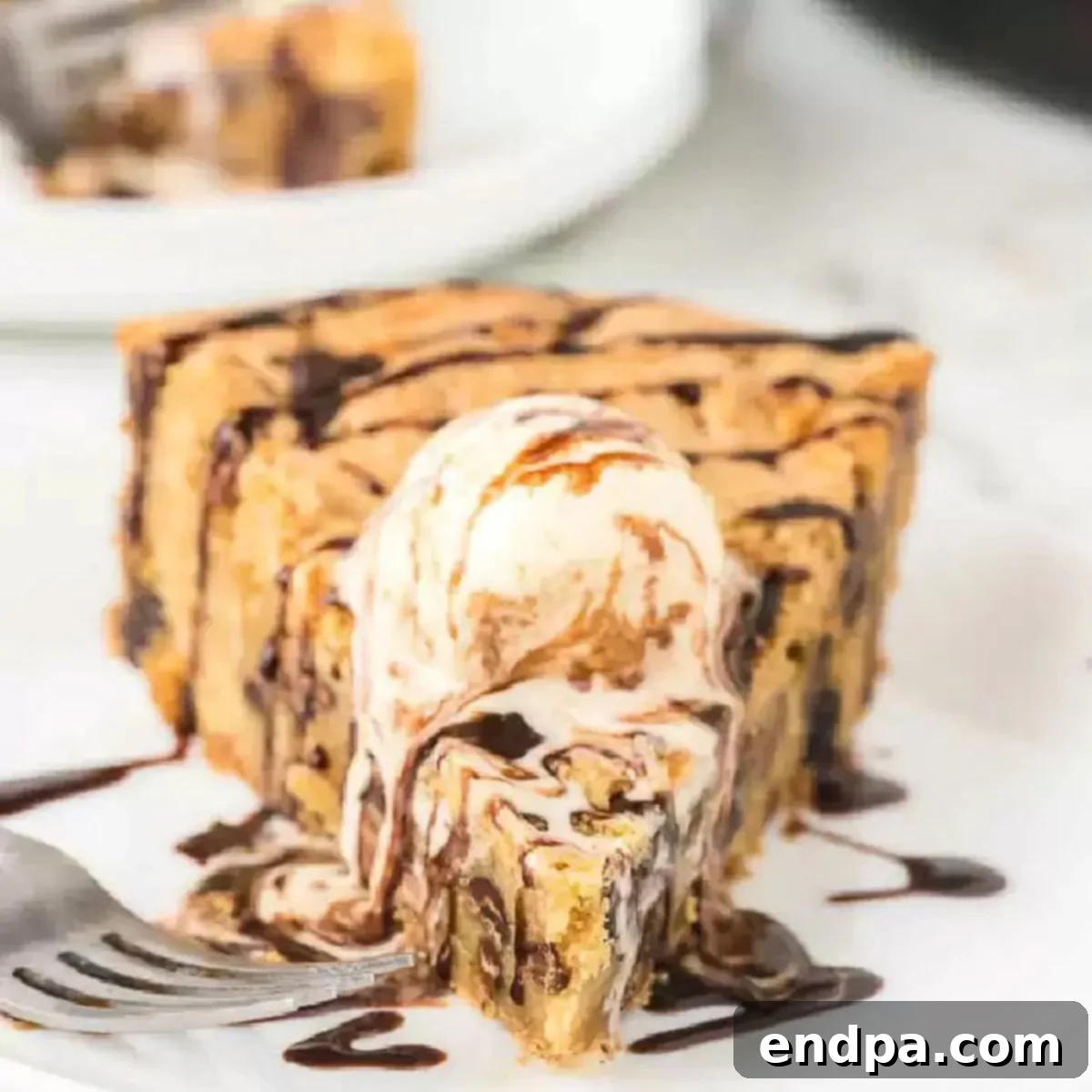 A slice of chocolate chip pizookie topped with vanilla ice cream and chocolate syrup