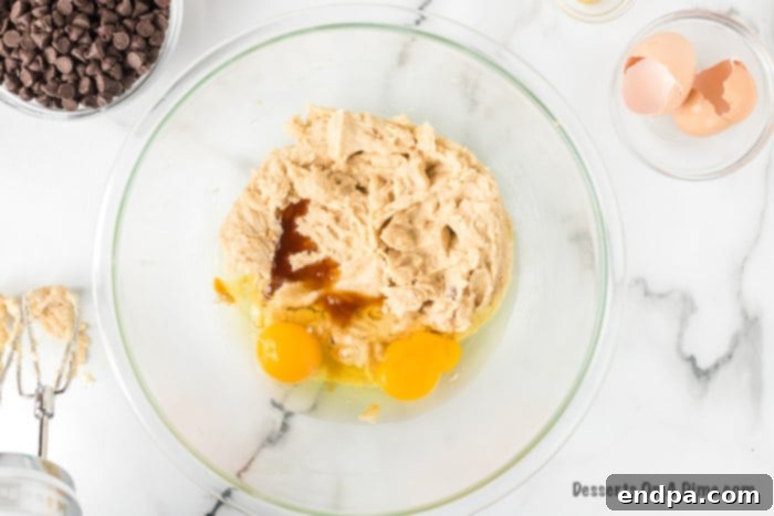 Mixing bowl showing eggs and vanilla extract added to the creamed butter and sugar mixture, ready to be combined.