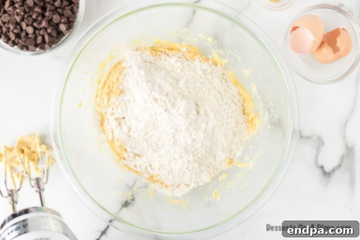 Dry ingredients, including flour, salt, and baking soda, being poured into the wet mixture in a mixing bowl.