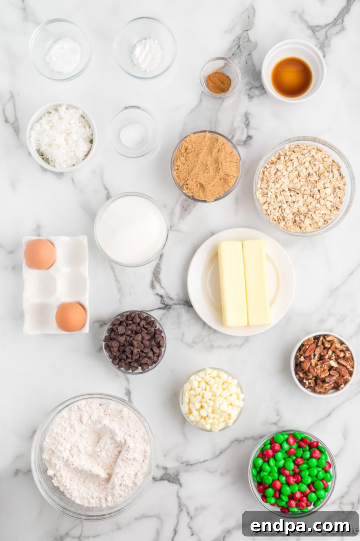 Festive Frontier Cookies 3 A flat lay image of all essential ingredients for Christmas Cowboy Cookies including flour, baking soda, baking powder, cinnamon, salt, butter, sugar, brown sugar, eggs, vanilla extract, oats, chocolate chips, pecans, coconut, and M&M's.