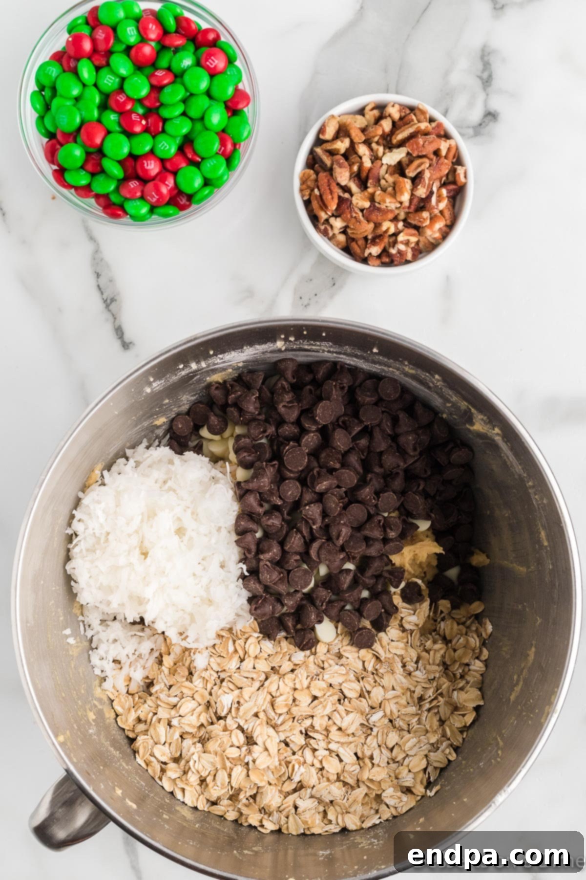 Festive Frontier Cookies 8 Folding in the oats, chocolate chips (semi-sweet and white), chopped pecans, sweetened coconut flakes, and half of the red and green M&M's into the cookie dough.