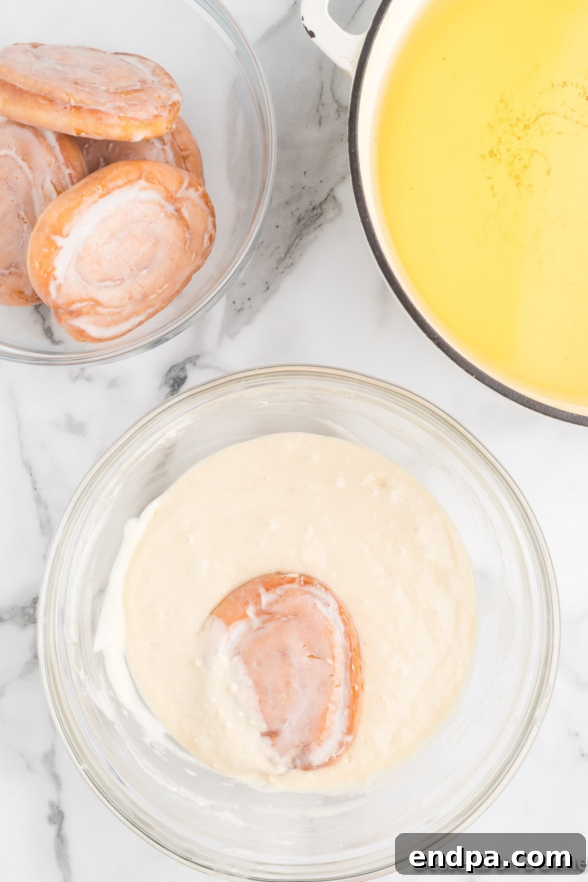 A honey bun being carefully dipped into the pancake batter mixture.