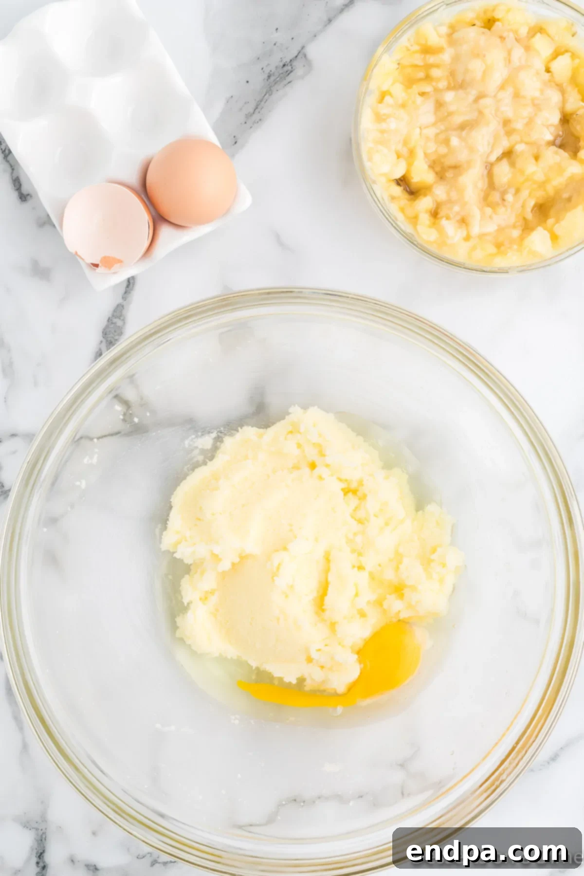 Eggs added to the butter and sugar mixture in a bowl, ready to be mixed.
