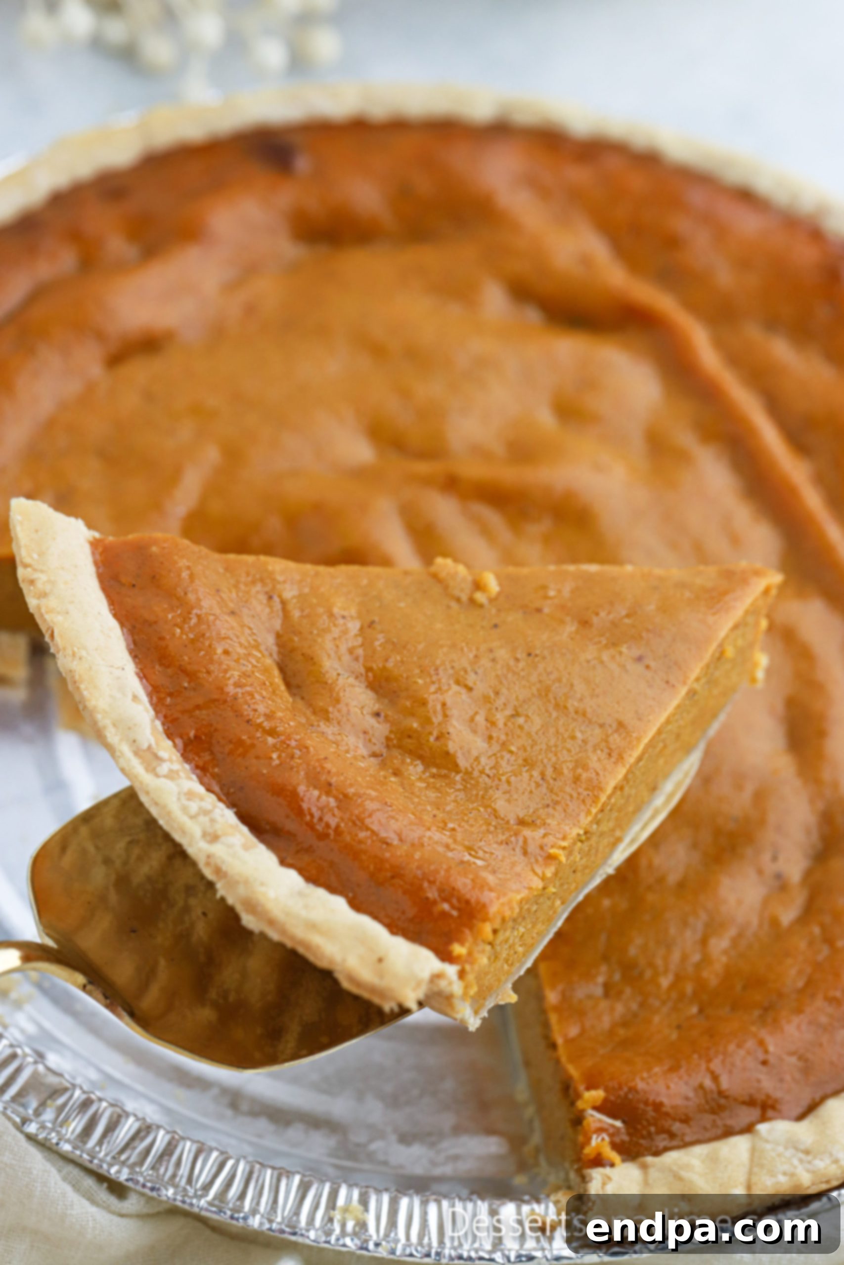 A beautifully sliced pumpkin pie topped with whipped cream, ready for serving.