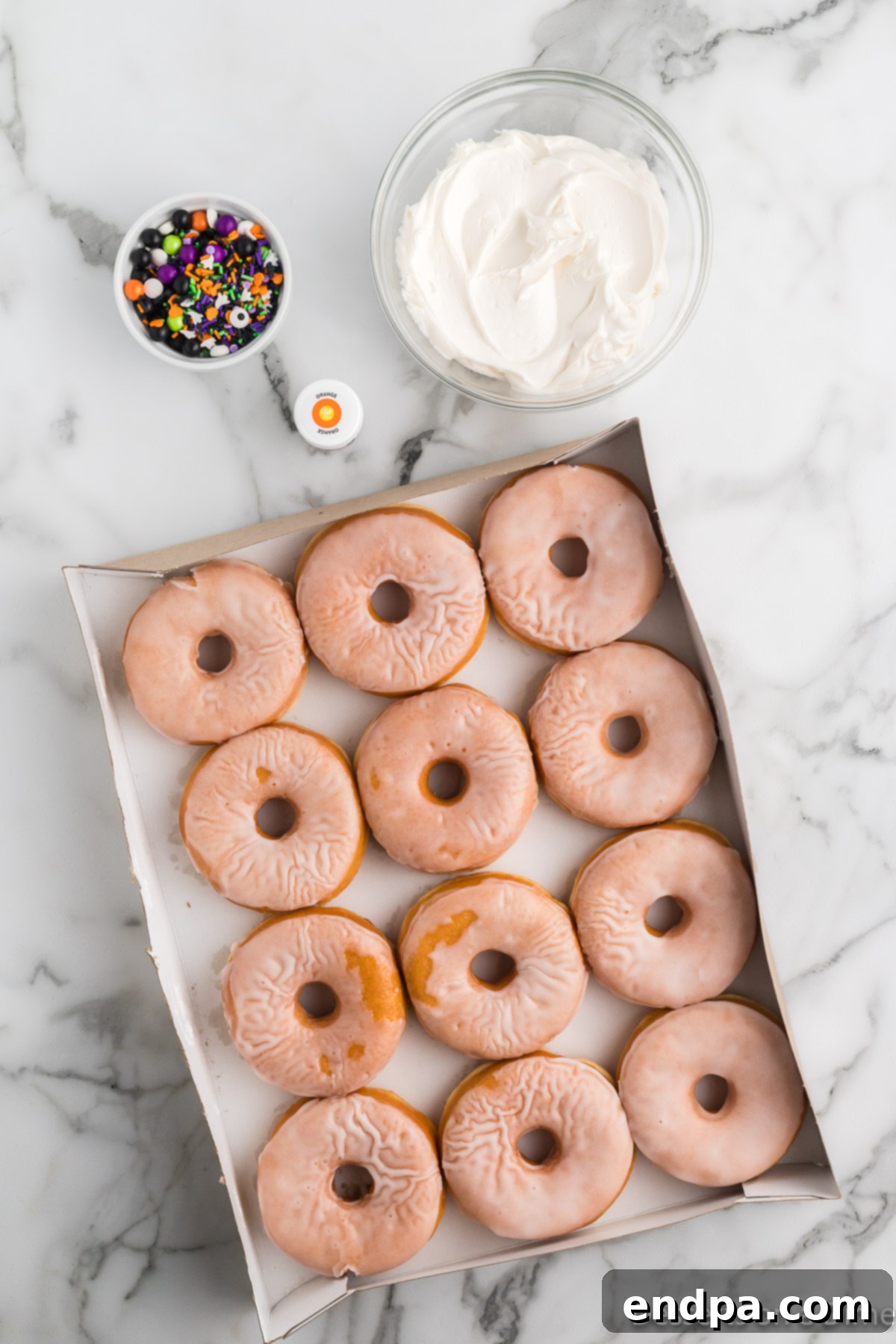 Spooky Delicious Halloween Donuts 3 Ingredients for Halloween Donuts: glazed donuts, white frosting, orange food coloring, Halloween sprinkles.