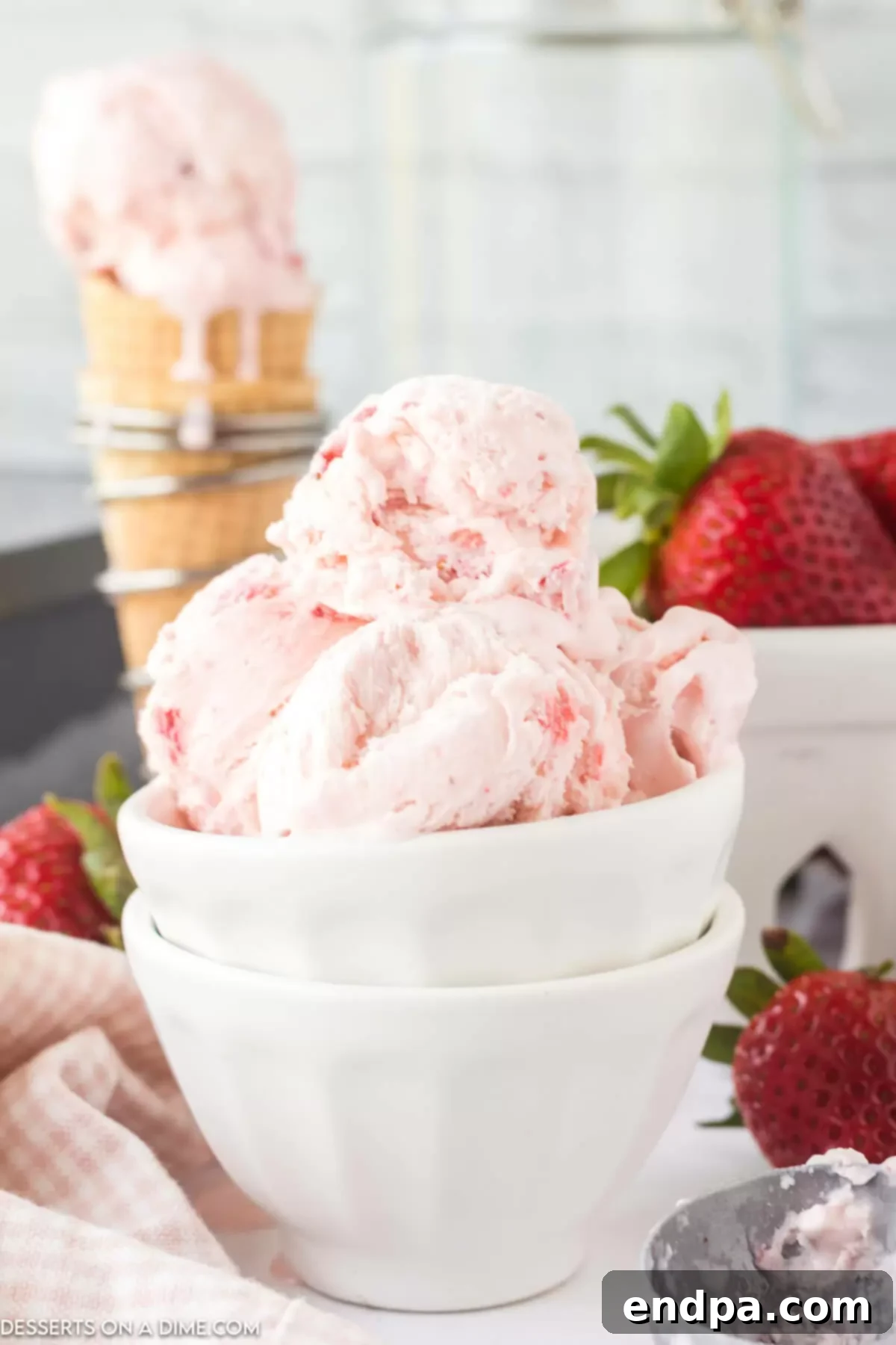 Scoops of creamy No-Churn Strawberry Ice Cream in a bowl, garnished with fresh strawberries.