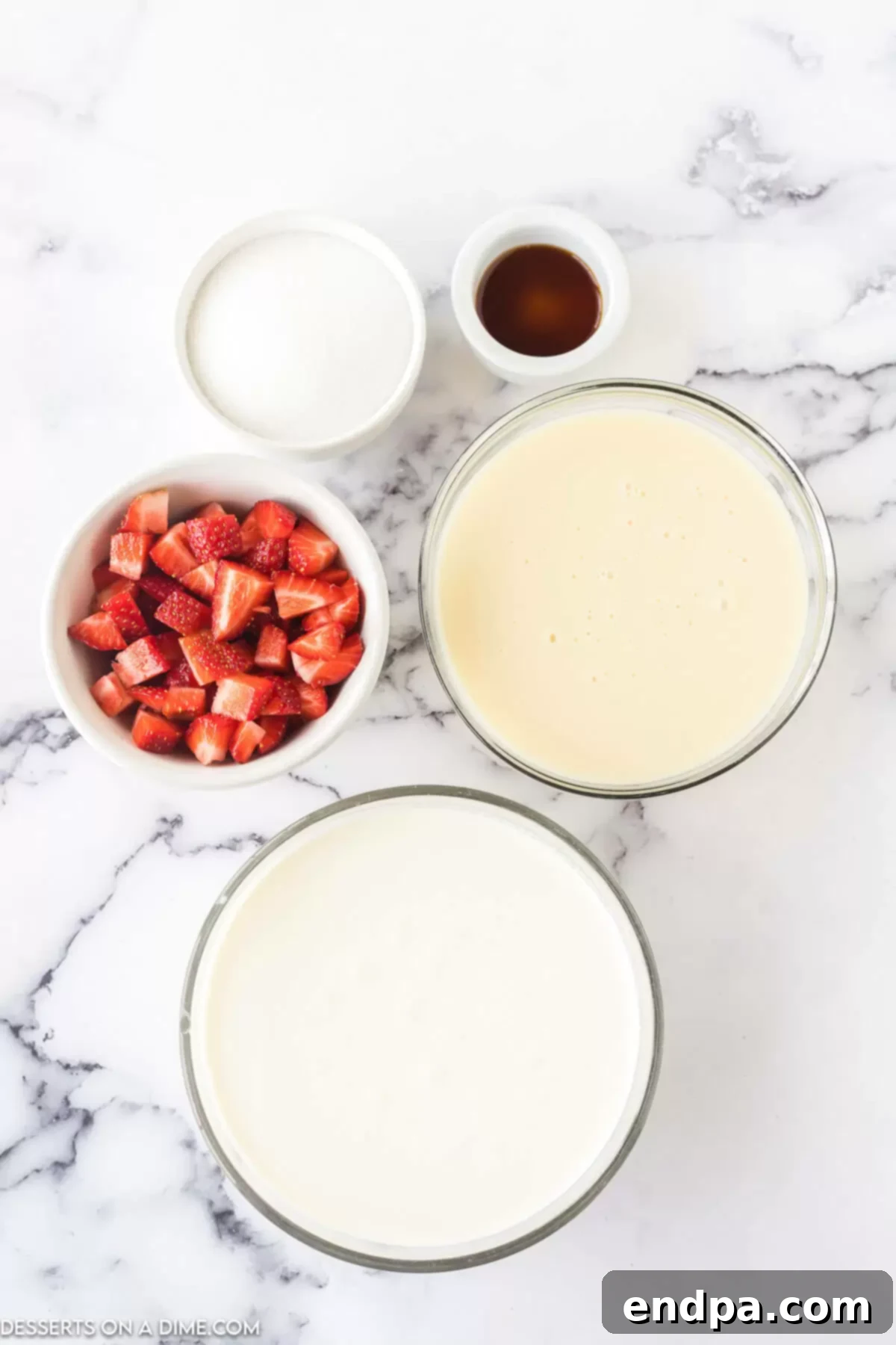 A flat lay of the key ingredients for No-Churn Strawberry Ice Cream: heavy whipping cream, vanilla extract, sweetened condensed milk, diced fresh strawberries, and granulated sugar.