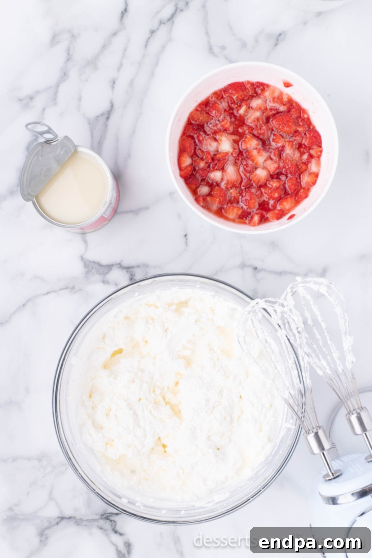 A mixing bowl with heavy whipping cream and vanilla extract, being whipped to stiff peaks.