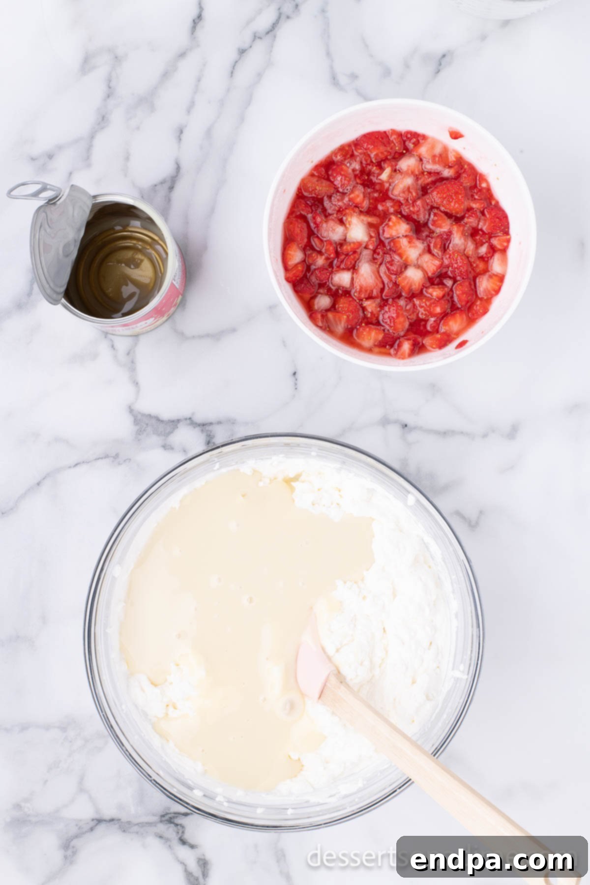 Sweetened condensed milk being poured into the whipped cream mixture in a bowl.