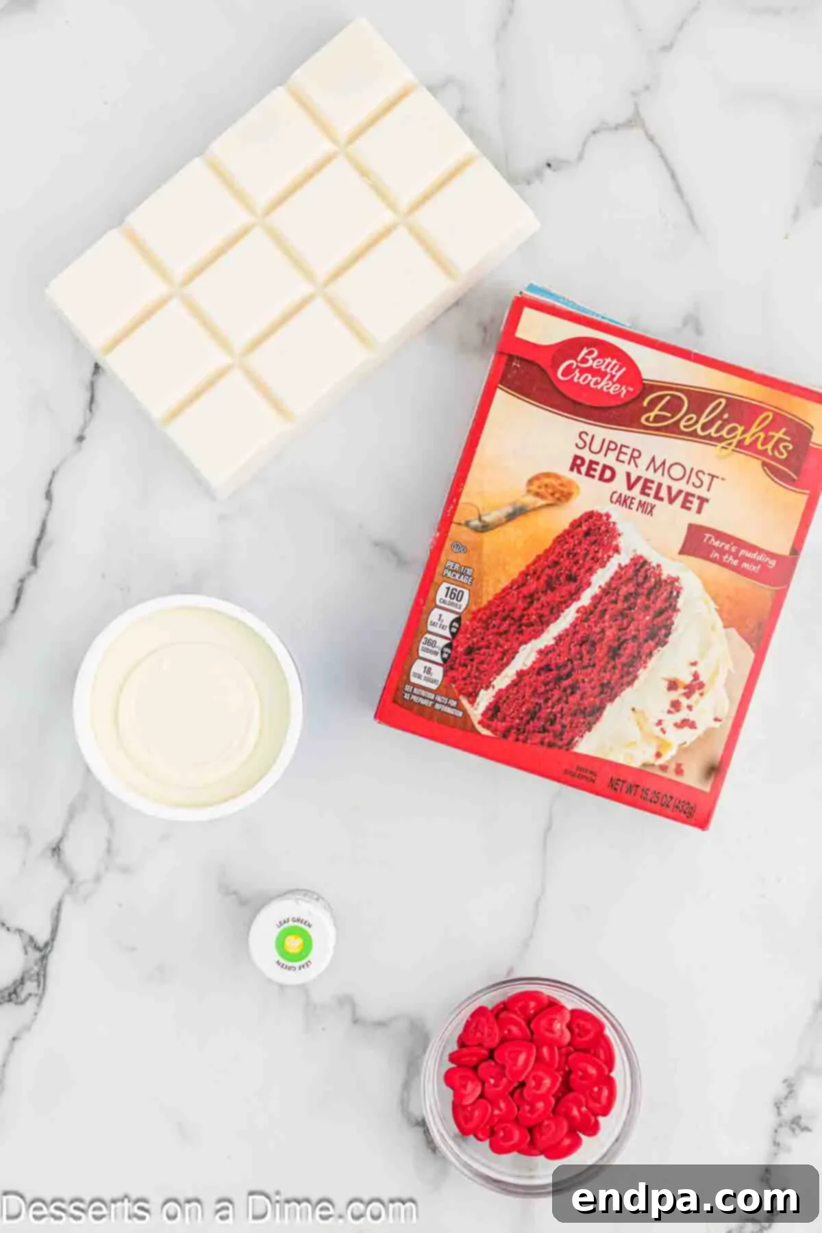 Grinchmas Cake Bites 3 Ingredients laid out for Grinch Cake Balls, including a red velvet cake mix, cream cheese frosting, white almond bark, green gel food coloring, and red heart sprinkles.