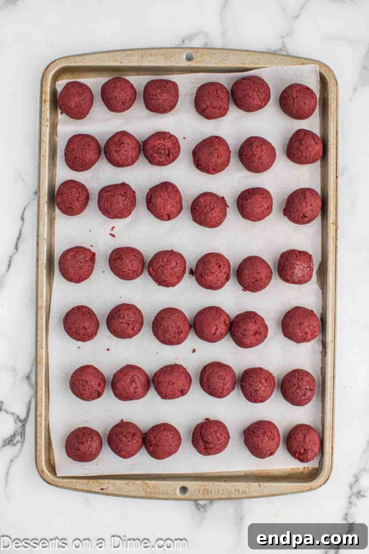 Grinchmas Cake Bites 6 Uniformly shaped cake balls arranged on a parchment-lined cookie sheet, ready for chilling.