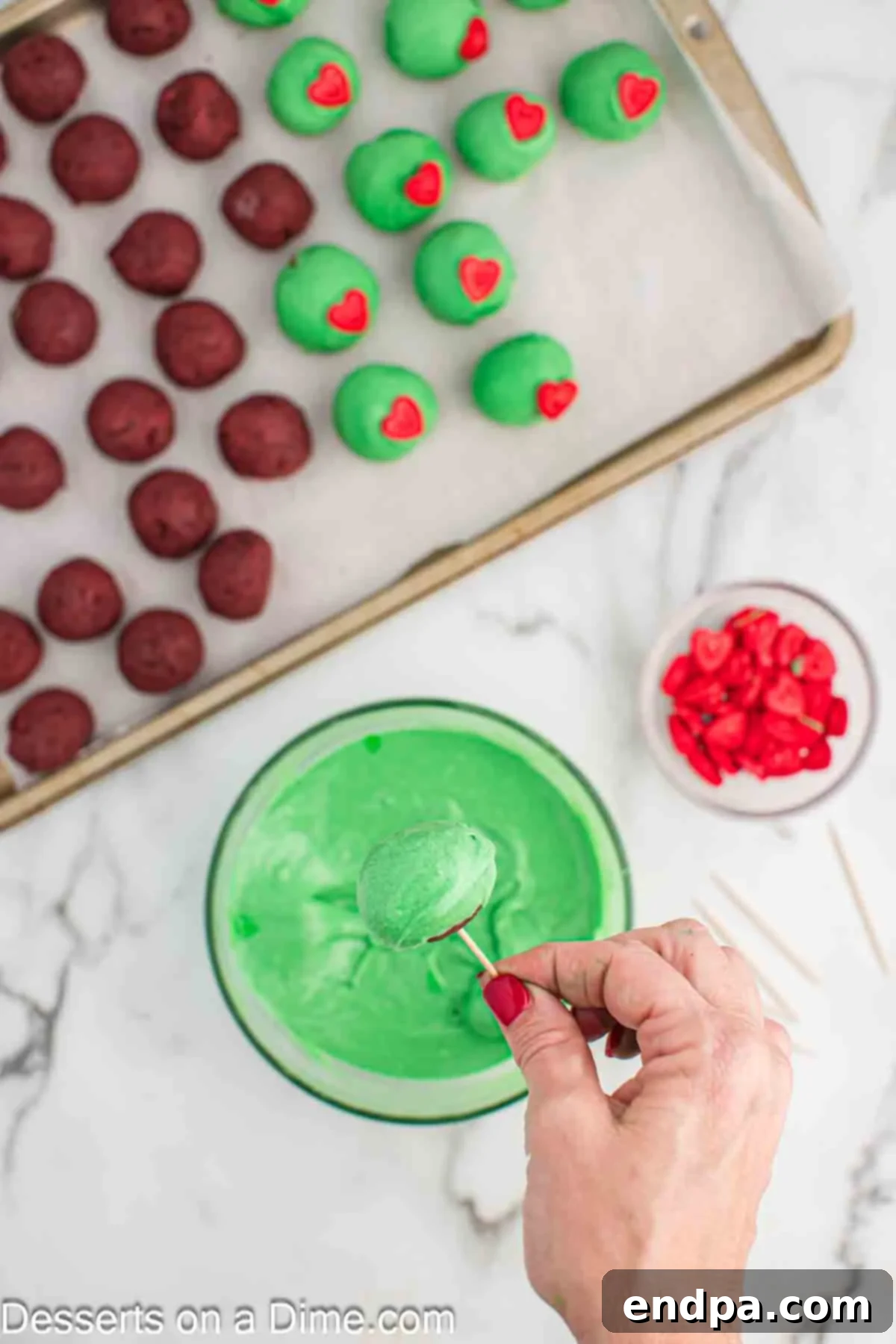 Grinchmas Cake Bites 7 Green-colored melted almond bark in a bowl with a cake ball being dipped.