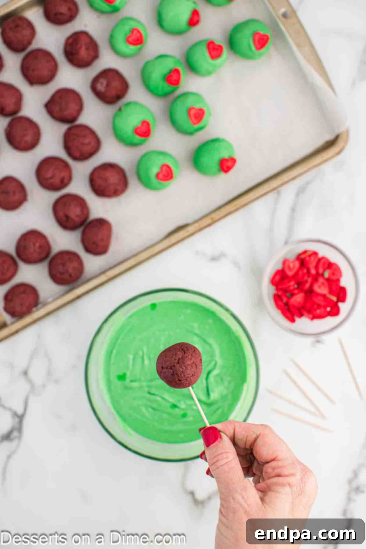 Grinchmas Cake Bites 9 Additional Grinch Cake Balls being dipped in melted green coating.
