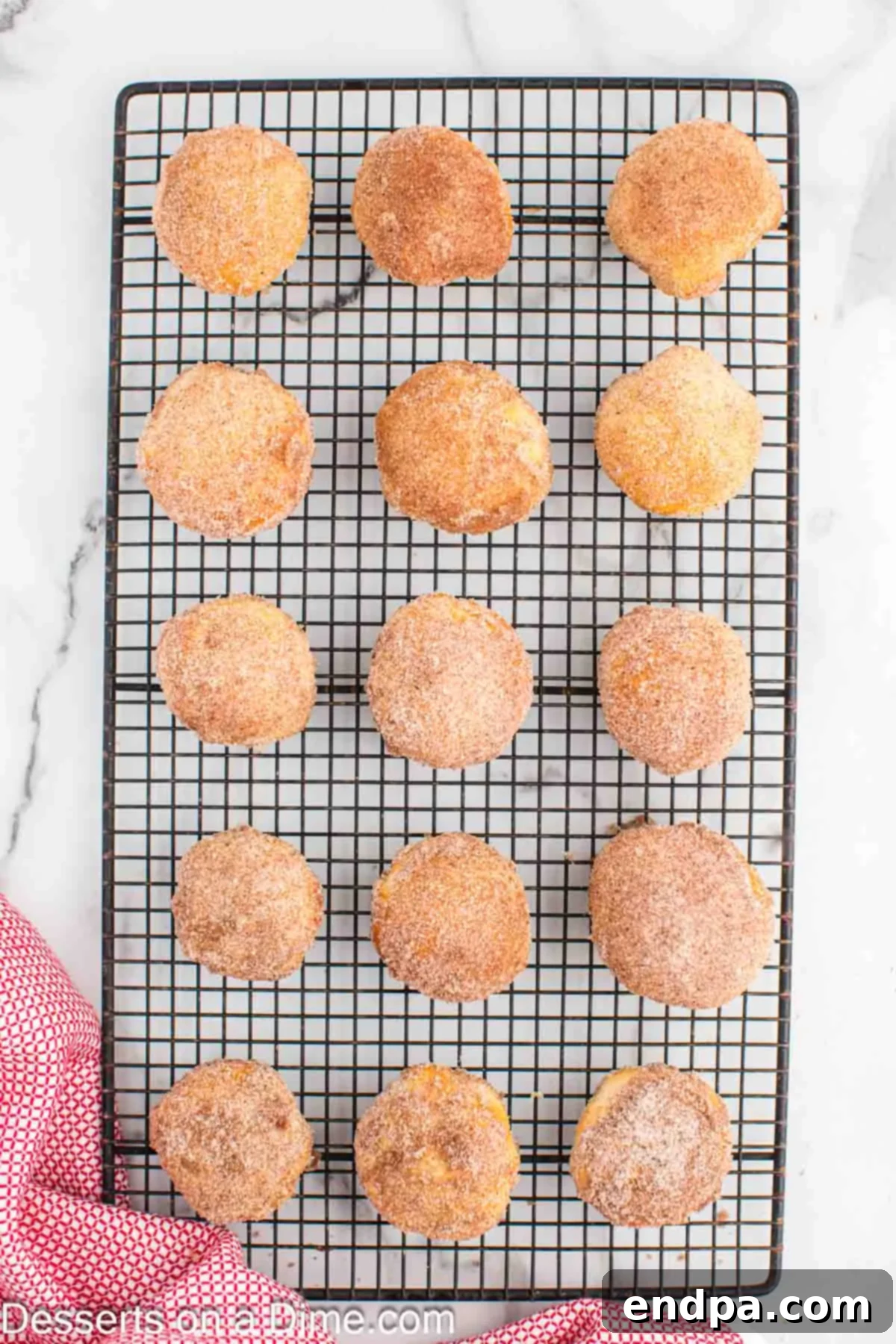 Air Fryer Apple Pie Bites 11 Hot apple pie bombs being rolled in a bowl of cinnamon and sugar mixture, ready for cooling.