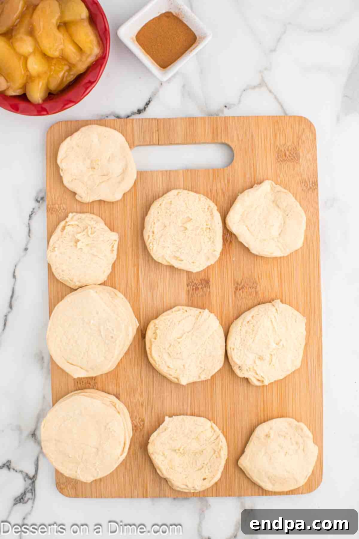 Air Fryer Apple Pie Bites 4 Biscuits on a cutting board being carefully separated into individual layers.