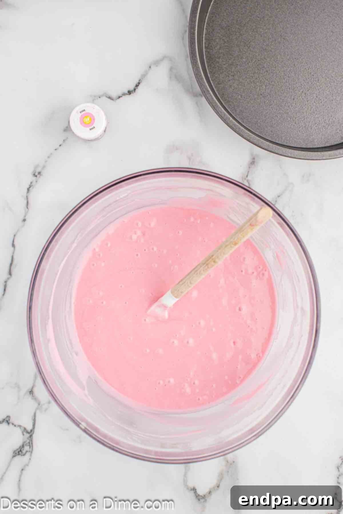 Cake batter in bowl with pink food coloring.