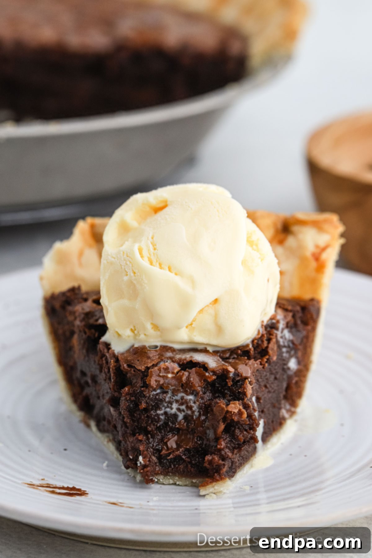 Brownie pie sliced and topped with ice cream.