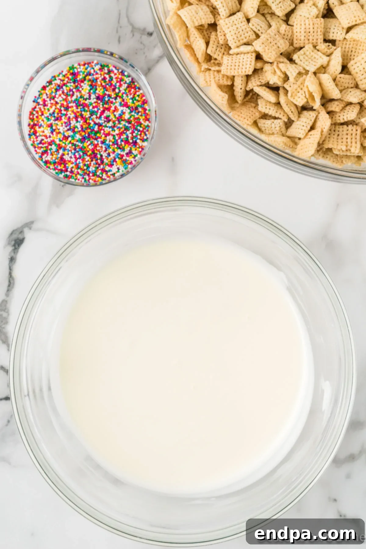 Festive Funfetti Snack Mix 4 Melted almond bark in a clear glass bowl, glistening and smooth