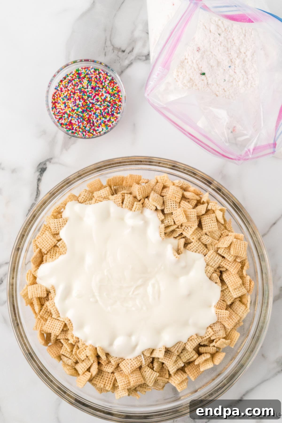 Festive Funfetti Snack Mix 6 Melted white chocolate being carefully poured over the Chex cereal in a mixing bowl