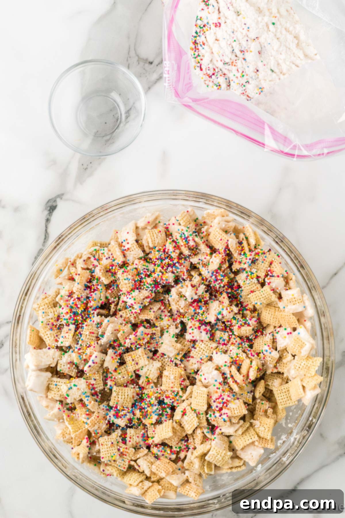 Festive Funfetti Snack Mix 7 Vibrant multi-colored sprinkles being generously scattered over chocolate-coated Chex cereal