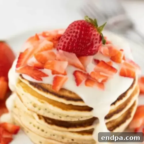 Strawberry Pancakes with a generous swirl of cream cheese glaze and fresh strawberries.