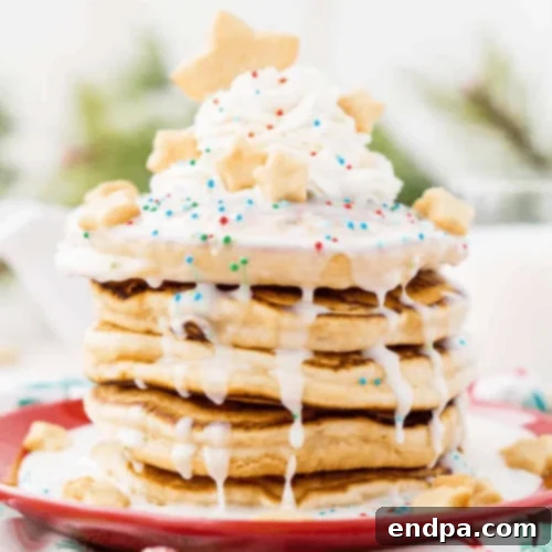 Sugar Cookie Pancakes piled high with icing, whipped cream, and sprinkles.
