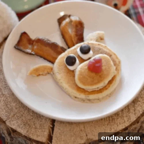Plate of decorated Reindeer Pancakes with pretzel antlers and candy eyes.