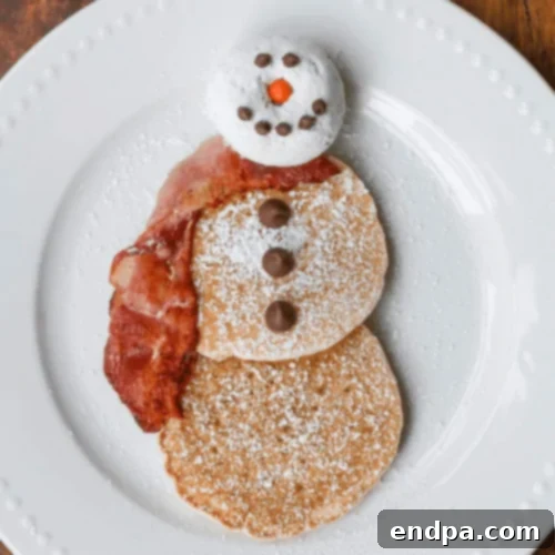Adorable Snowman Pancakes decorated with chocolate chips and candies.