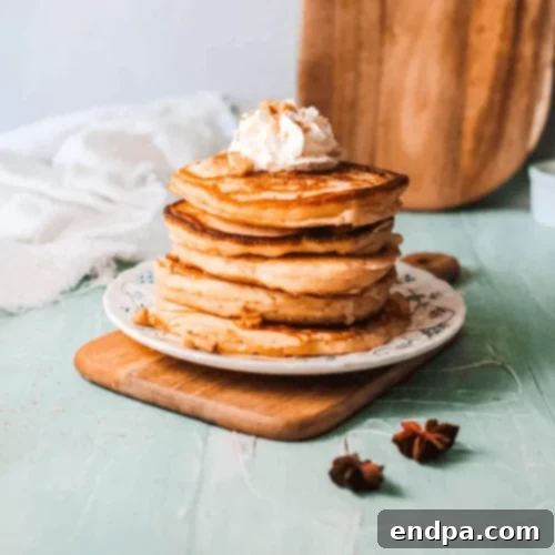 Eggnog Pancakes stacked with whipped cream and a sprinkle of nutmeg.