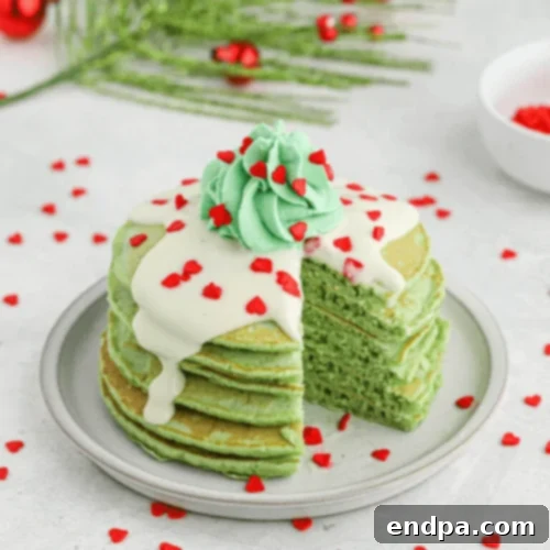Grinch Pancakes topped with green whipped cream and a red candy heart.