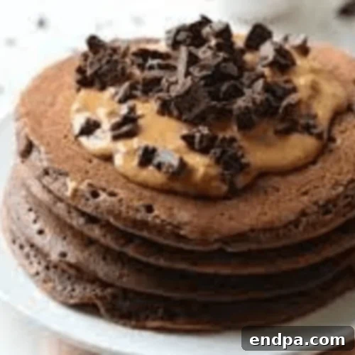 Double Chocolate Peanut Butter Pancakes stacked with peanut butter and chocolate drizzle.