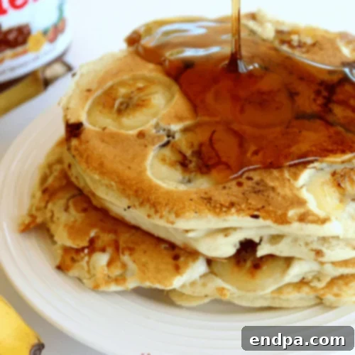 Nutella Stuffed Banana Pancakes topped with Nutella and banana slices.