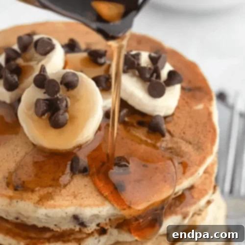 Fluffy Banana Chocolate Chip Pancakes topped with banana slices and chocolate chips.