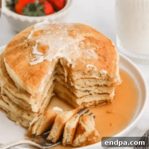 A stack of golden-brown Cracker Barrel Pancakes with butter and syrup.