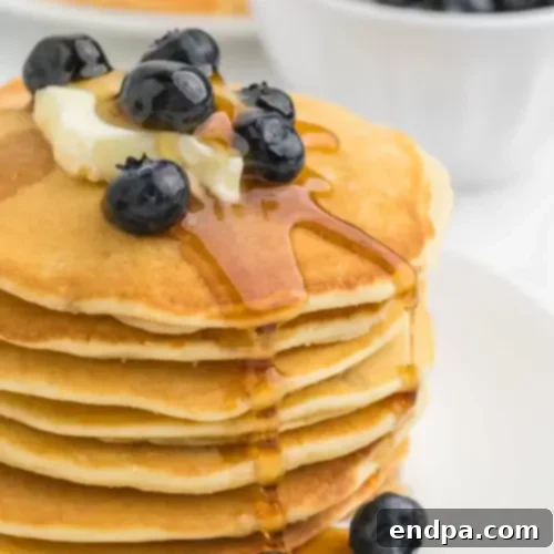 A stack of Sweet Cream Pancakes with syrup and berries.