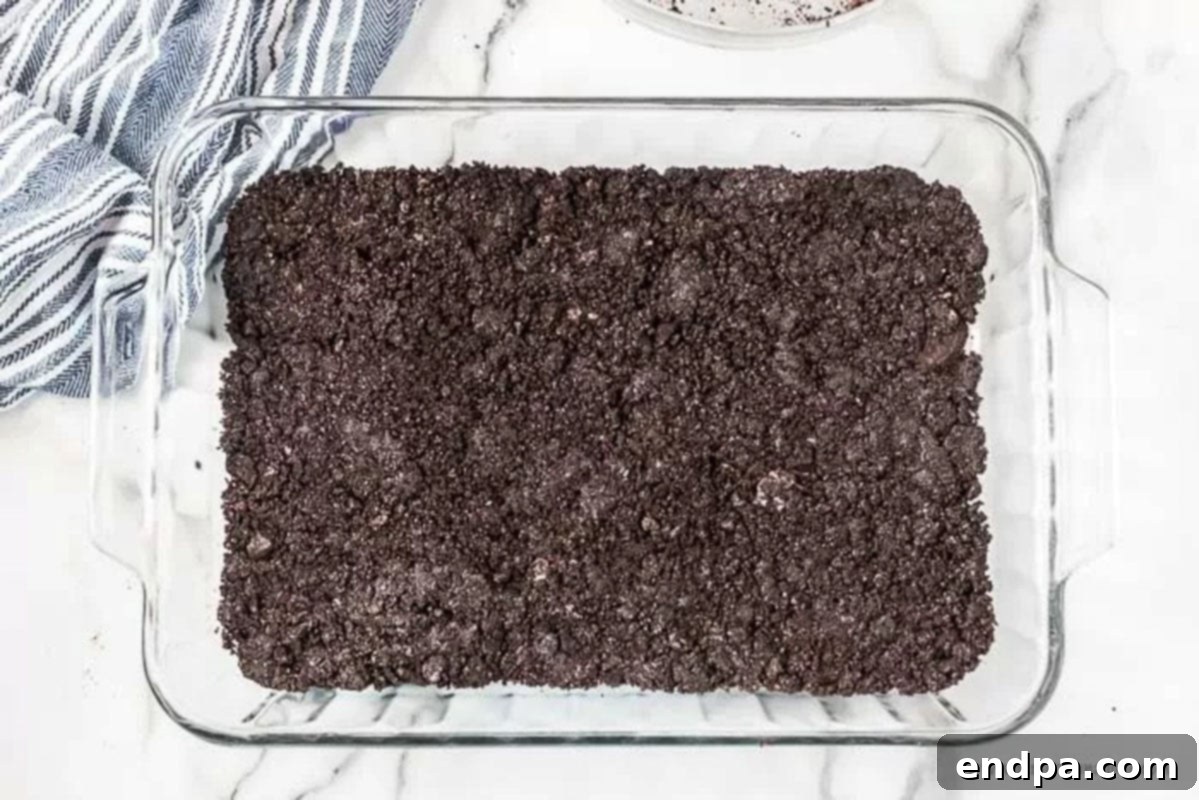 Crushed Oreo cookies mixed with melted butter and pressed firmly into the bottom of a baking dish to form the crust.